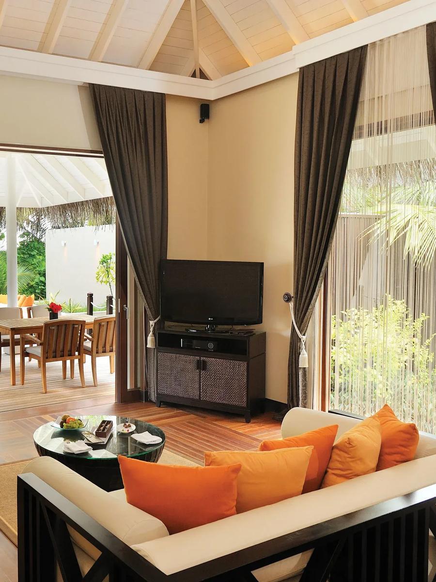 A Sunset Beach Suite's living room opening onto its pool deck and dining table