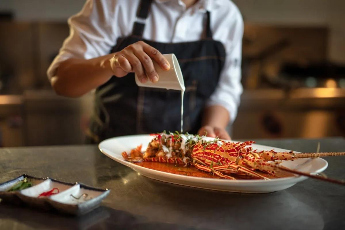 A chef plating a whole grilled lobster at Sea Dragon, Kandima's Far East fine-dining restaurant