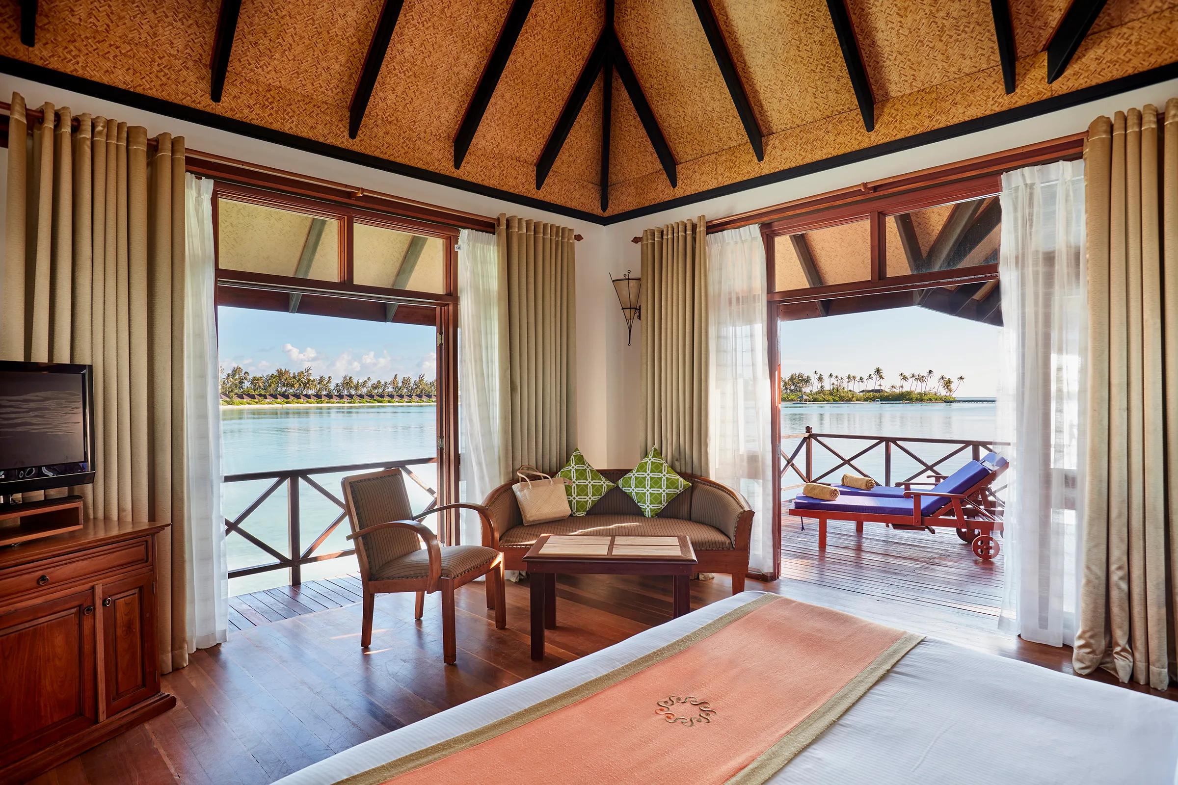 Bedroom interior of a Water Villa on Main Island, opening onto a private overwater deck