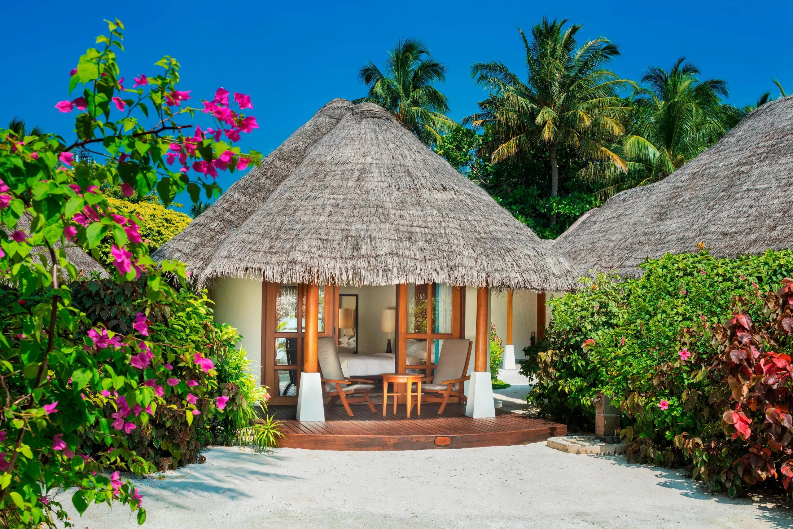 A thatched-roof Cottage villa exterior, with a private terrace and bougainvillea framing the entrance