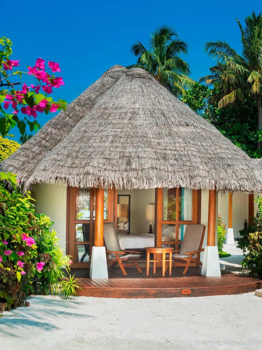 A thatched-roof Cottage villa exterior, with a private terrace and bougainvillea framing the entrance