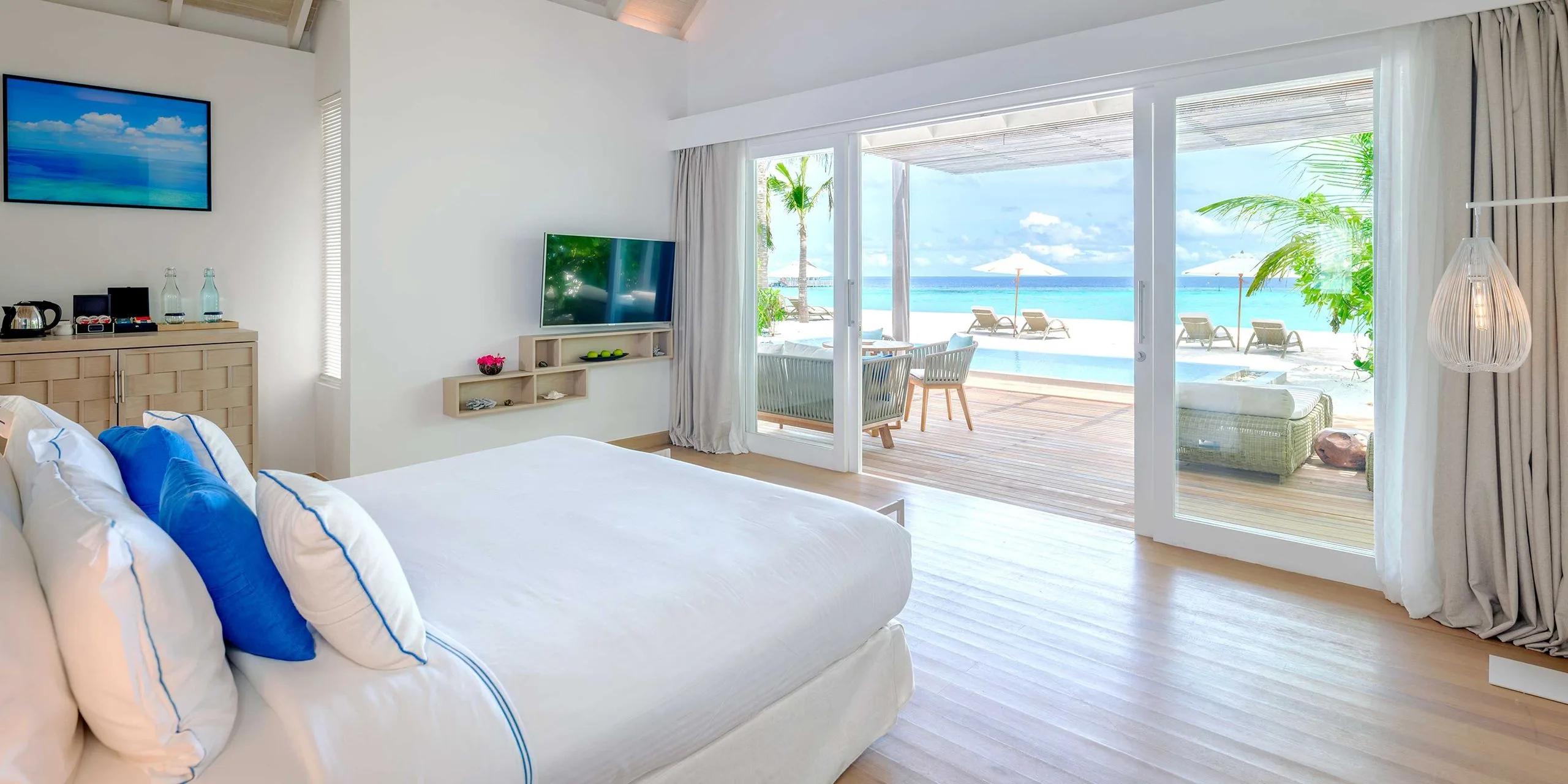 A Two-Bedroom Family Beach Villa with Pool's bedroom opening onto its private pool and the beach at Baglioni Maldives