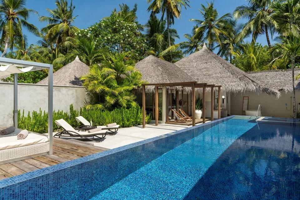 The private pool and thatched pavilion of a Honeymoon Pool Villa, set among palm gardens with loungers on the deck