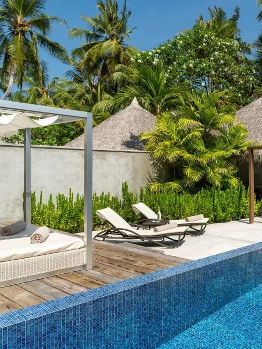 The private pool and thatched pavilion of a Honeymoon Pool Villa, set among palm gardens with loungers on the deck