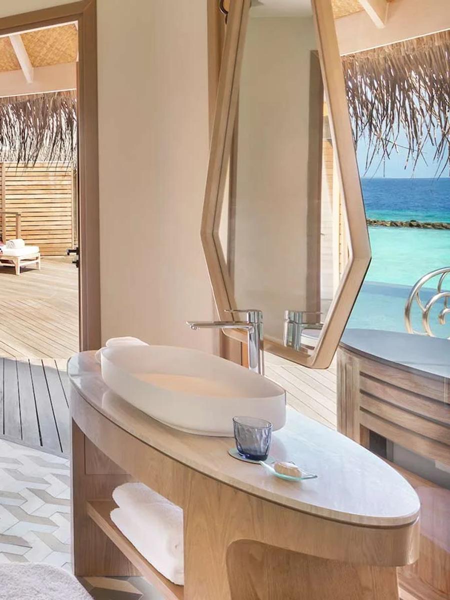 An Ocean House bathroom with a freestanding tub, opening directly onto the villa's overwater deck and loungers.