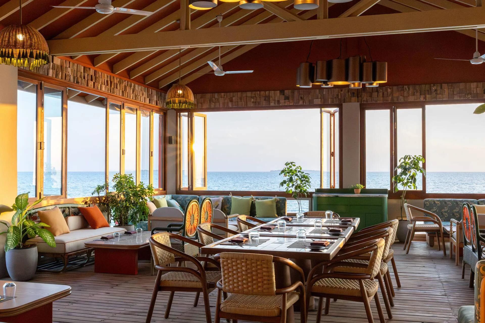 Onda's open-air overwater dining room at The Standard, tables set toward the ocean at sunset