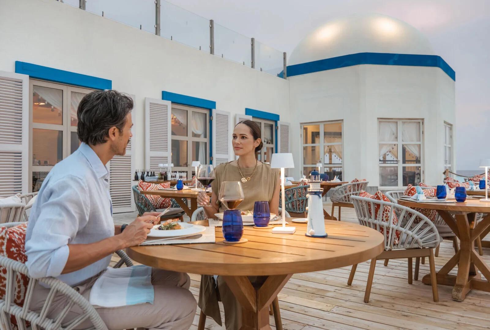 A couple dining on the terrace beneath The Lighthouse's domed blue-and-white structure