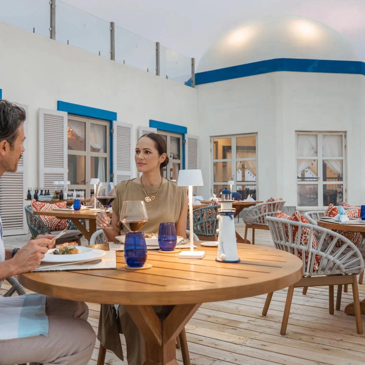A couple dining on the terrace beneath The Lighthouse's domed blue-and-white structure