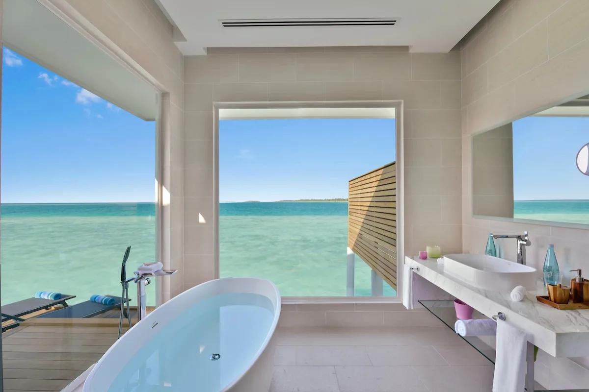 An Aqua Villa's overwater bathroom, with a freestanding tub facing the lagoon