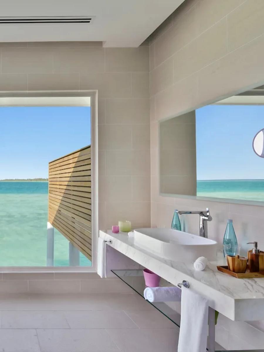 An Aqua Villa's overwater bathroom, with a freestanding tub facing the lagoon