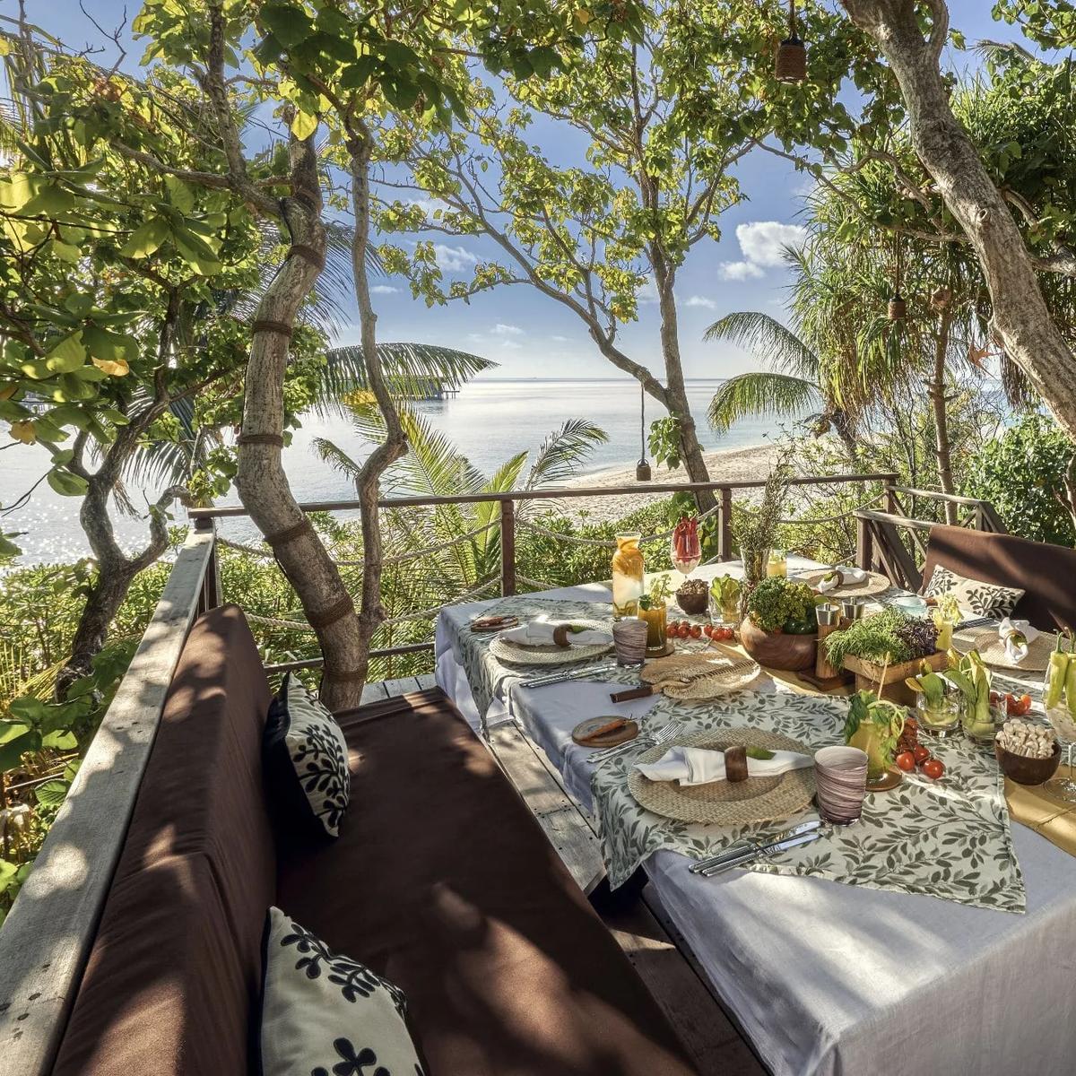 A table set for lunch on the elevated deck of Chef's Garden Treehouse, the beach visible through the trees