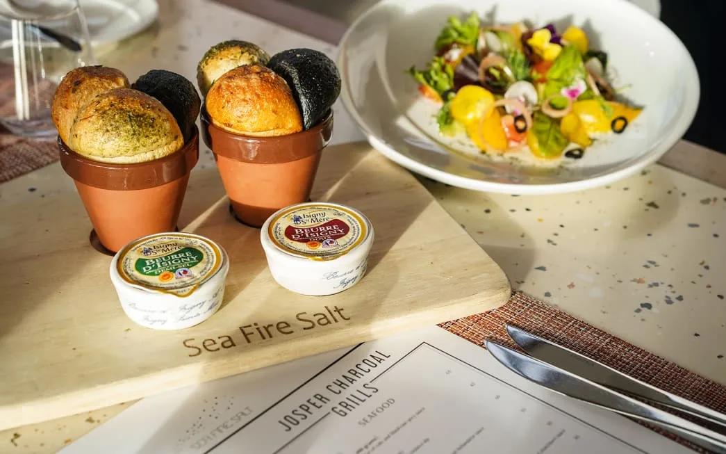 Bread, butter and a salad plate set on the Sea Fire Salt branded board