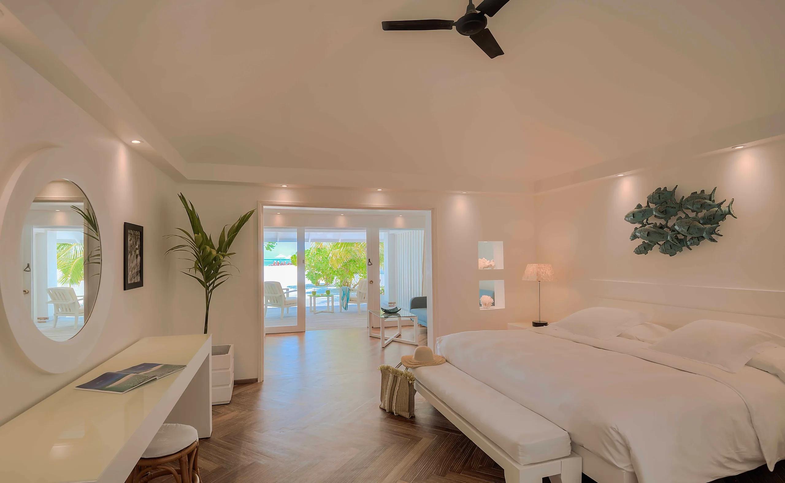 A Beach Front Junior Suite's terrace at sunrise, with palm and sea-almond trees framing the beach beyond