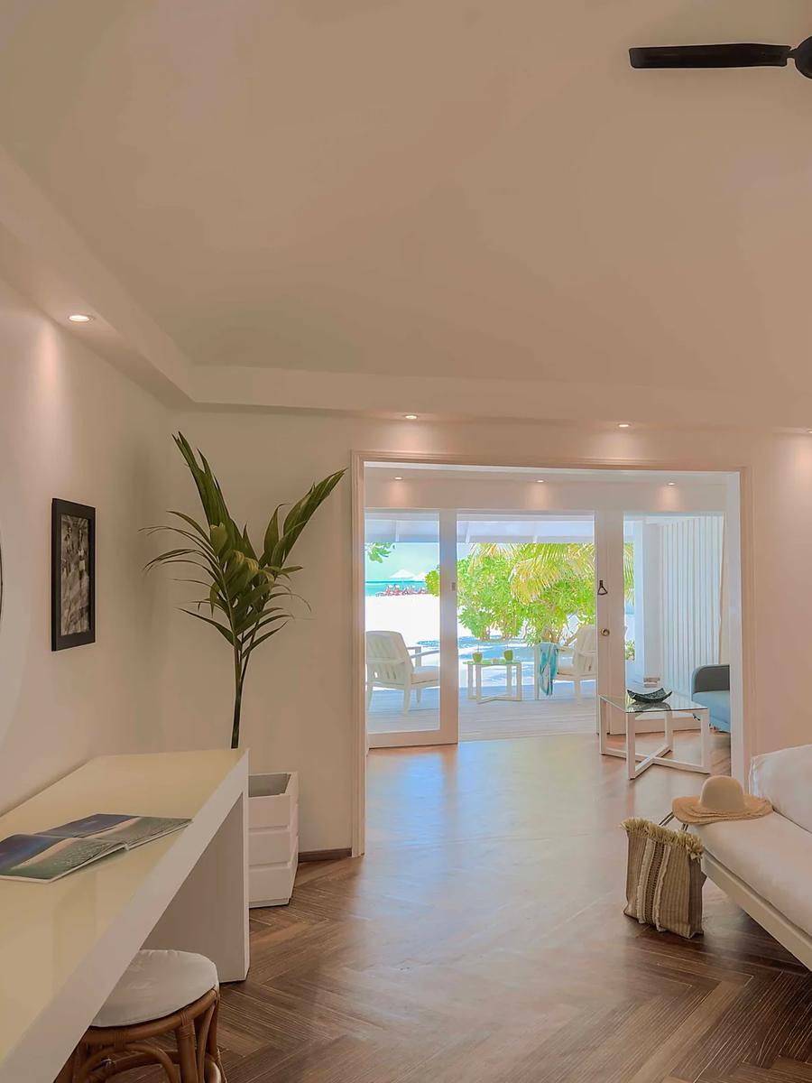 A Beach Front Junior Suite's terrace at sunrise, with palm and sea-almond trees framing the beach beyond