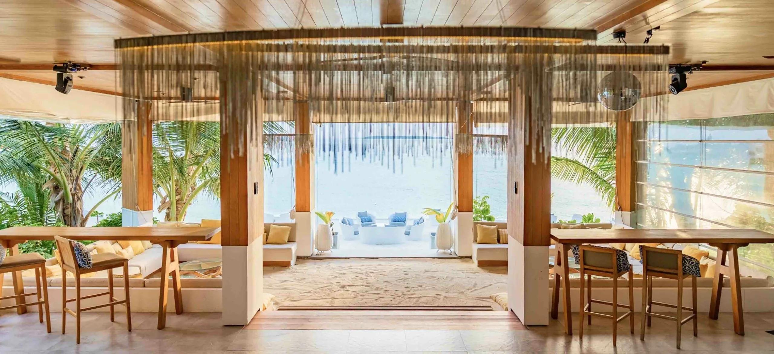 Baa Bar's lounge interior at Amilla, fringe curtains and a mirror ball over the ocean-facing bar