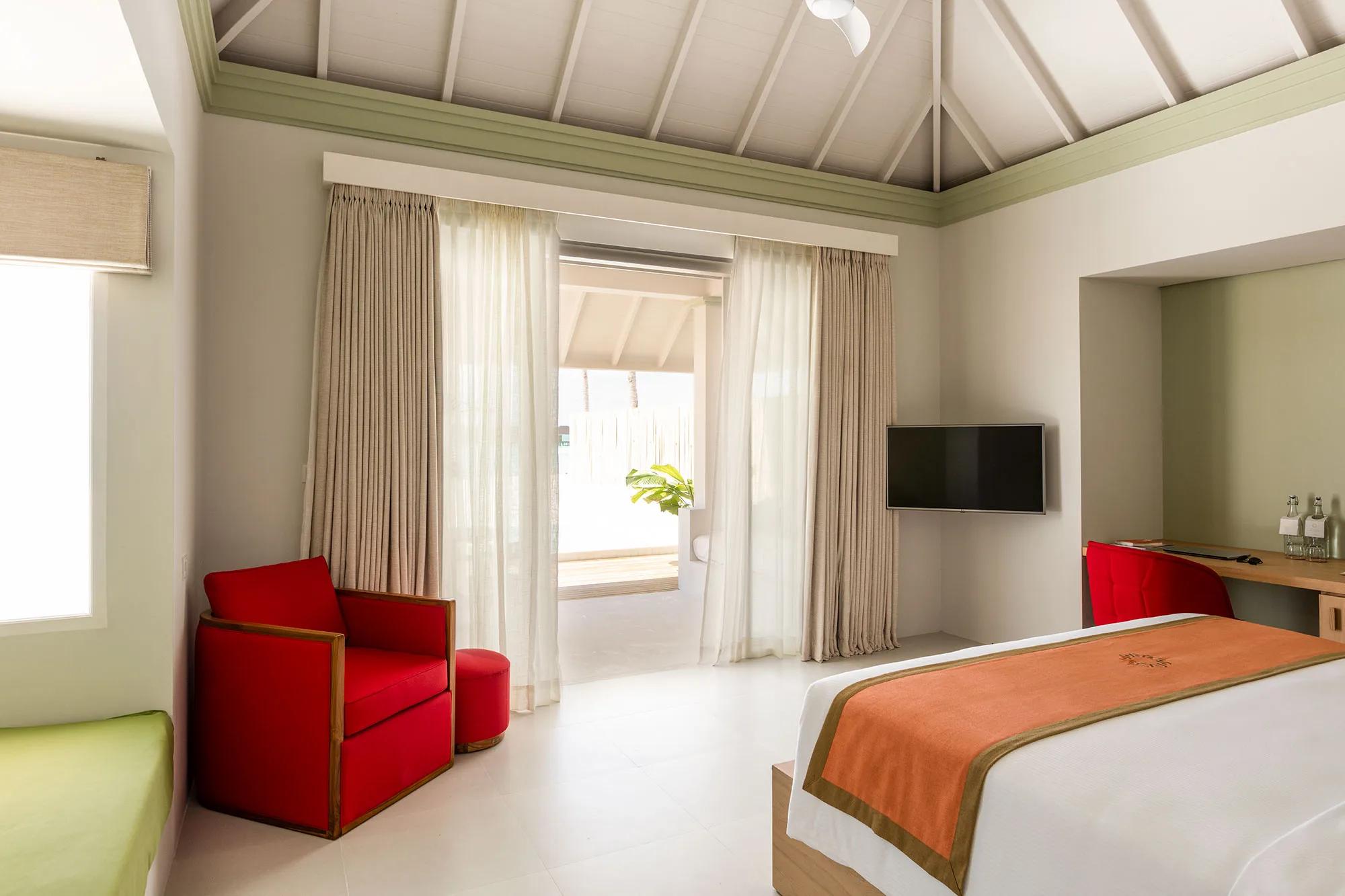Bedroom interior of a Grand Beach Villa with Pool at Sun Siyam Olhuveli, glass doors opening to the pool terrace