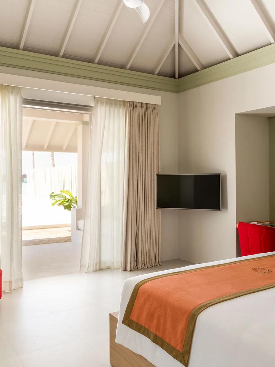 Bedroom interior of a Grand Beach Villa with Pool at Sun Siyam Olhuveli, glass doors opening to the pool terrace
