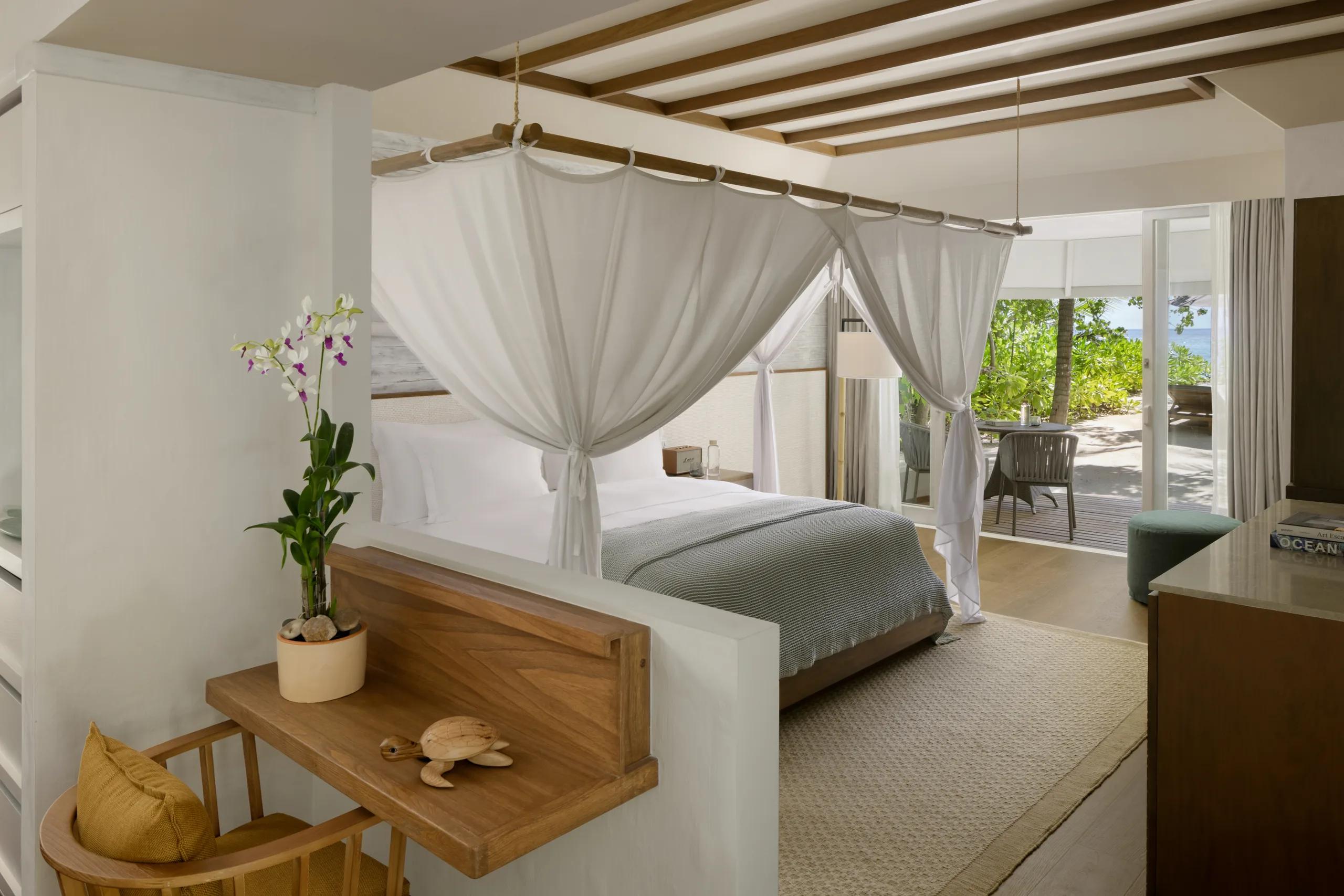Interior of a Beach Villa, a canopied king bed opening onto a private garden terrace.