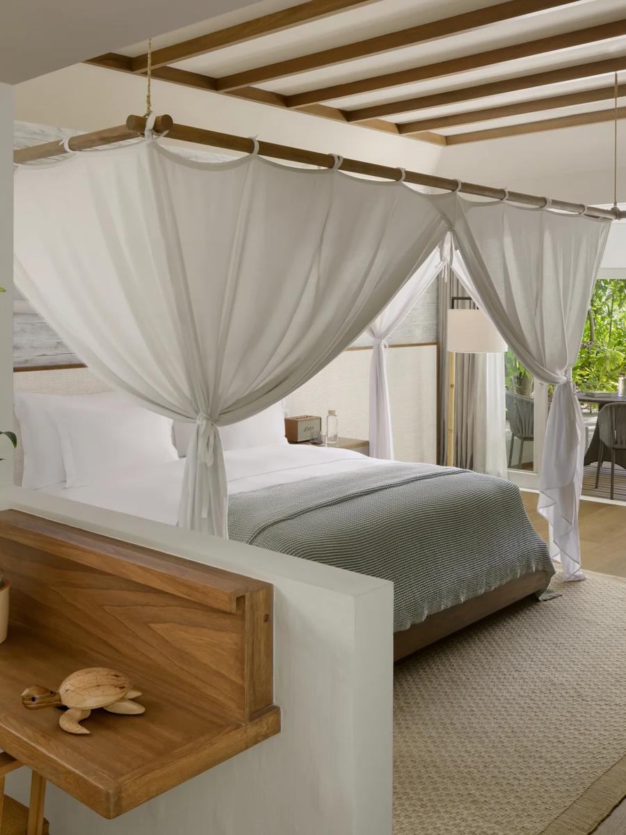 Interior of a Beach Villa, a canopied king bed opening onto a private garden terrace.