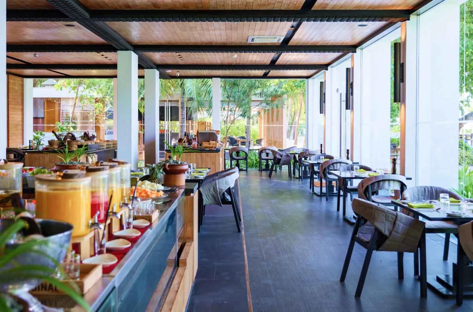 The buffet counter and dining room at FRESH, Amilla's breakfast restaurant, tables set beneath a wood-beamed roof