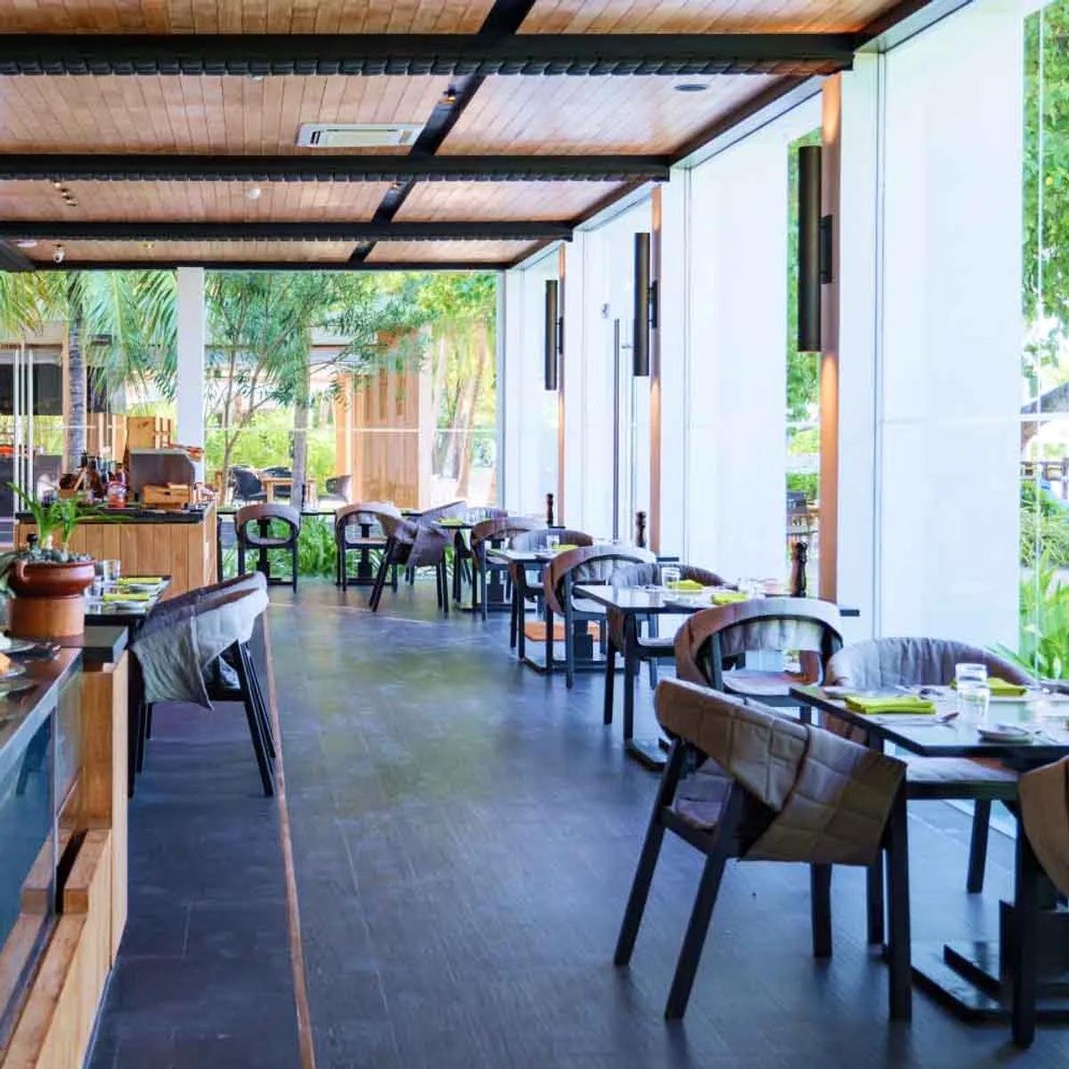The buffet counter and dining room at FRESH, Amilla's breakfast restaurant, tables set beneath a wood-beamed roof