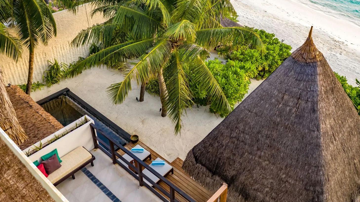An Earth Pool RESERVE Sunset villa's pool deck and sun loungers backing onto the beach at dusk