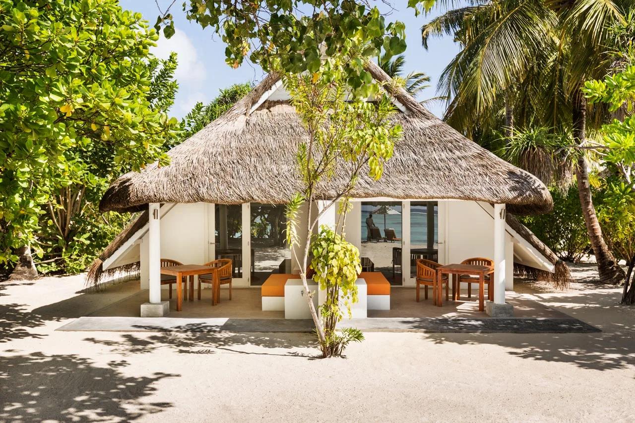 A thatched-roof Family Beach Pavilion with two separate dining terraces, shaded by palms and sea-almond trees