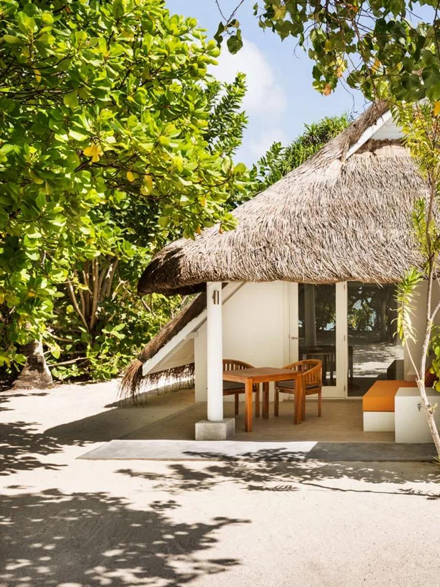 A thatched-roof Family Beach Pavilion with two separate dining terraces, shaded by palms and sea-almond trees