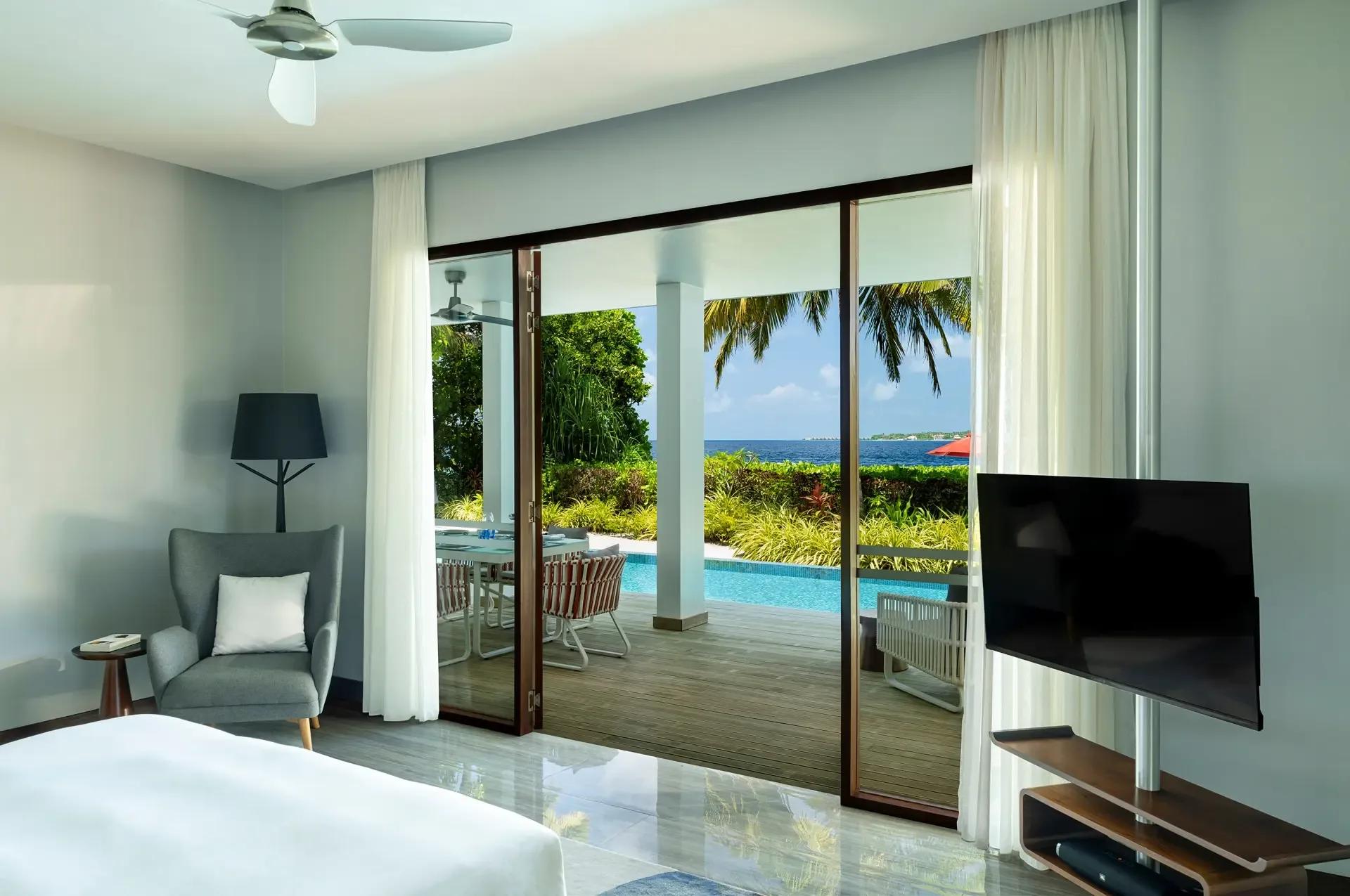 The private deck and pool of the Two-Bedroom Dhigali Suite, ocean visible past the sun umbrella