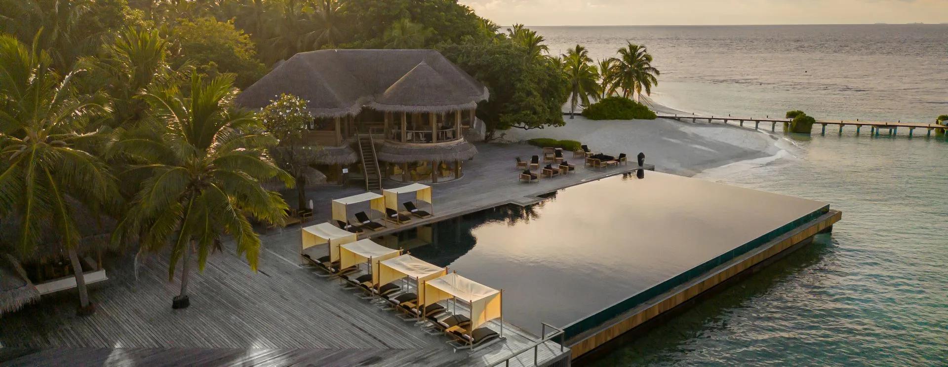 Latitude Bar's infinity pool deck and cabanas at sunset, overlooking the lagoon