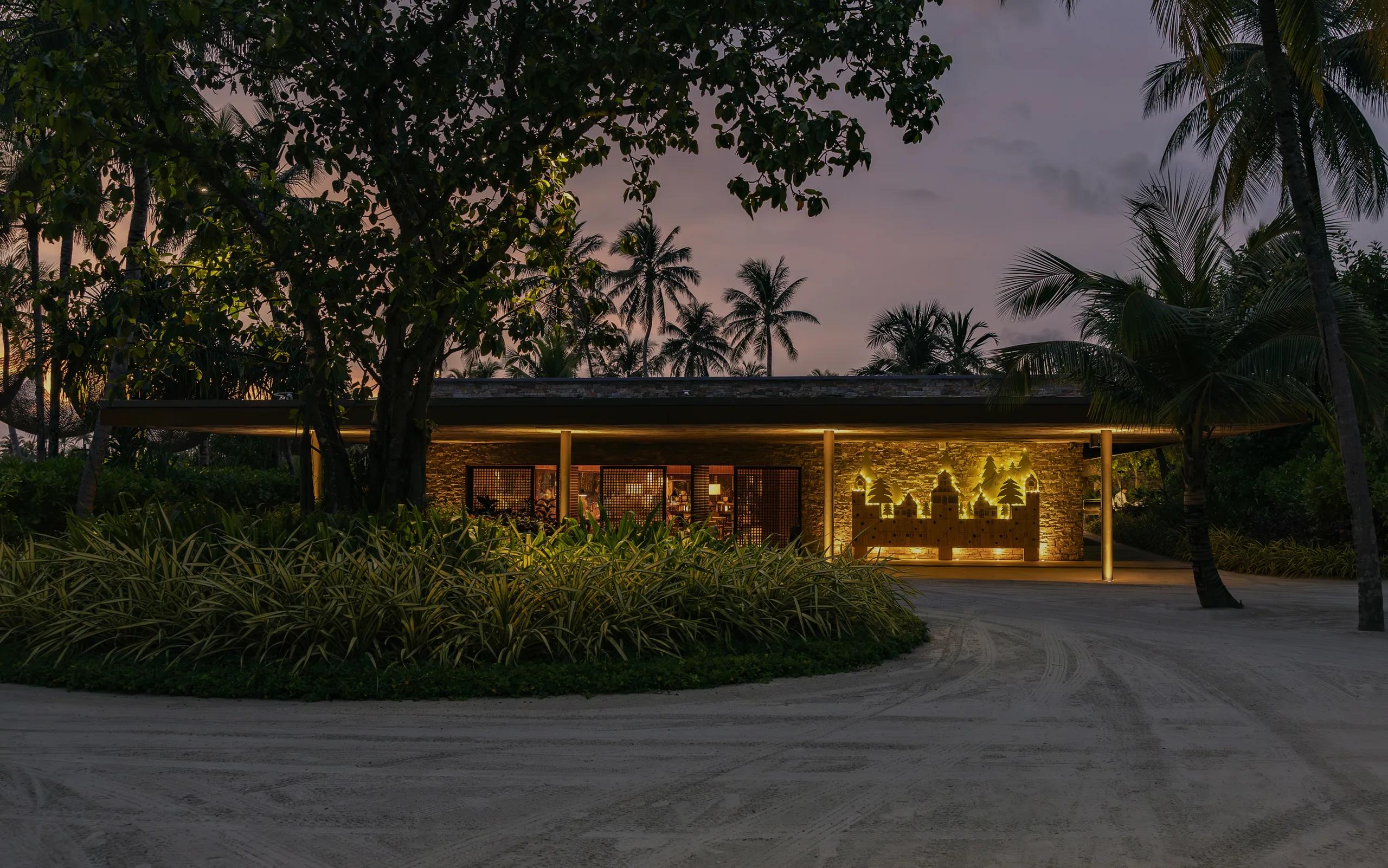 Portico's stone-walled pavilion lit at dusk, illuminated cut-out artwork set into its facade