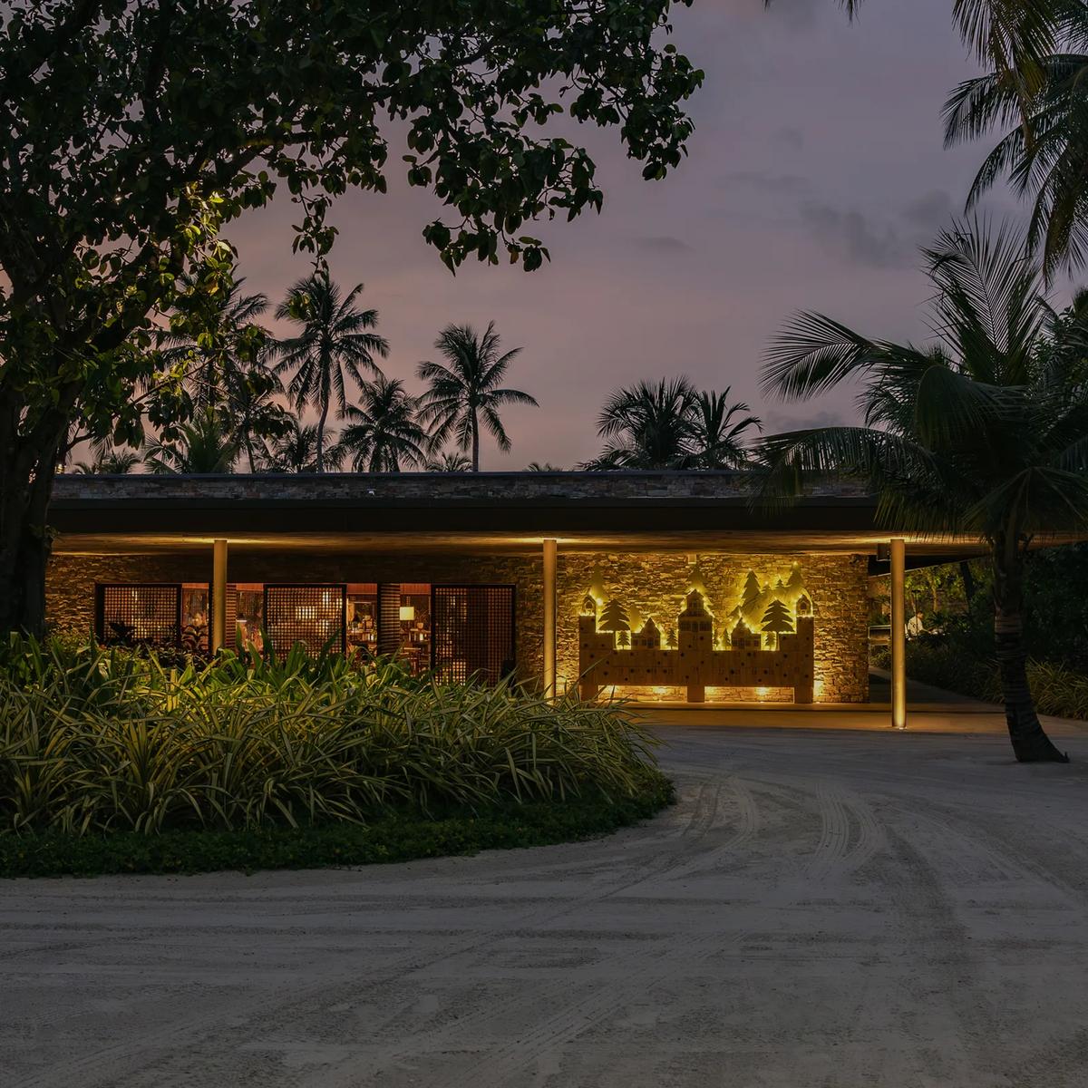 Portico's stone-walled pavilion lit at dusk, illuminated cut-out artwork set into its facade