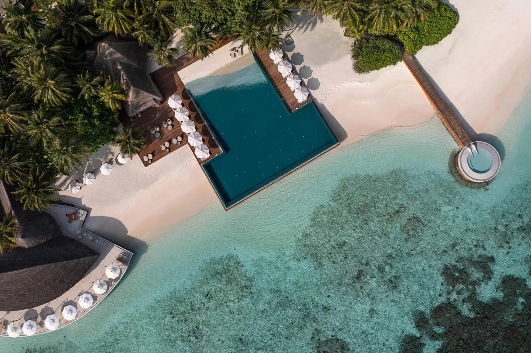 Aerial view of Huvafen Fushi's overwater pool deck and a circular plunge pool cantilevered at the end of a jetty