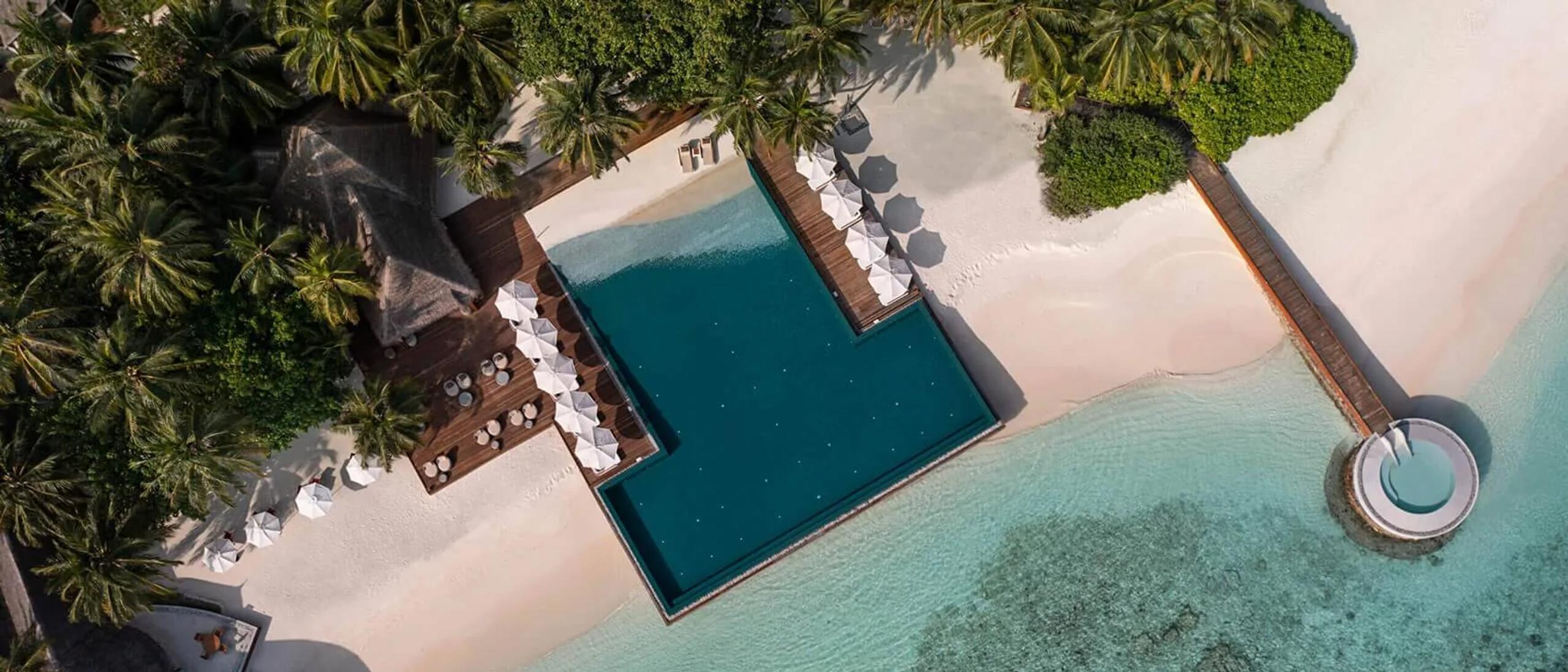 Aerial view of Huvafen Fushi's overwater pool deck and a circular plunge pool cantilevered at the end of a jetty