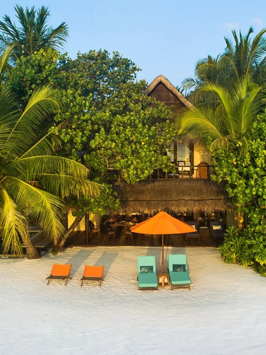 A Two Bedroom Sunset Beachfront Suite with Pool at golden hour, sun loungers set on the beach in front of its two storeys