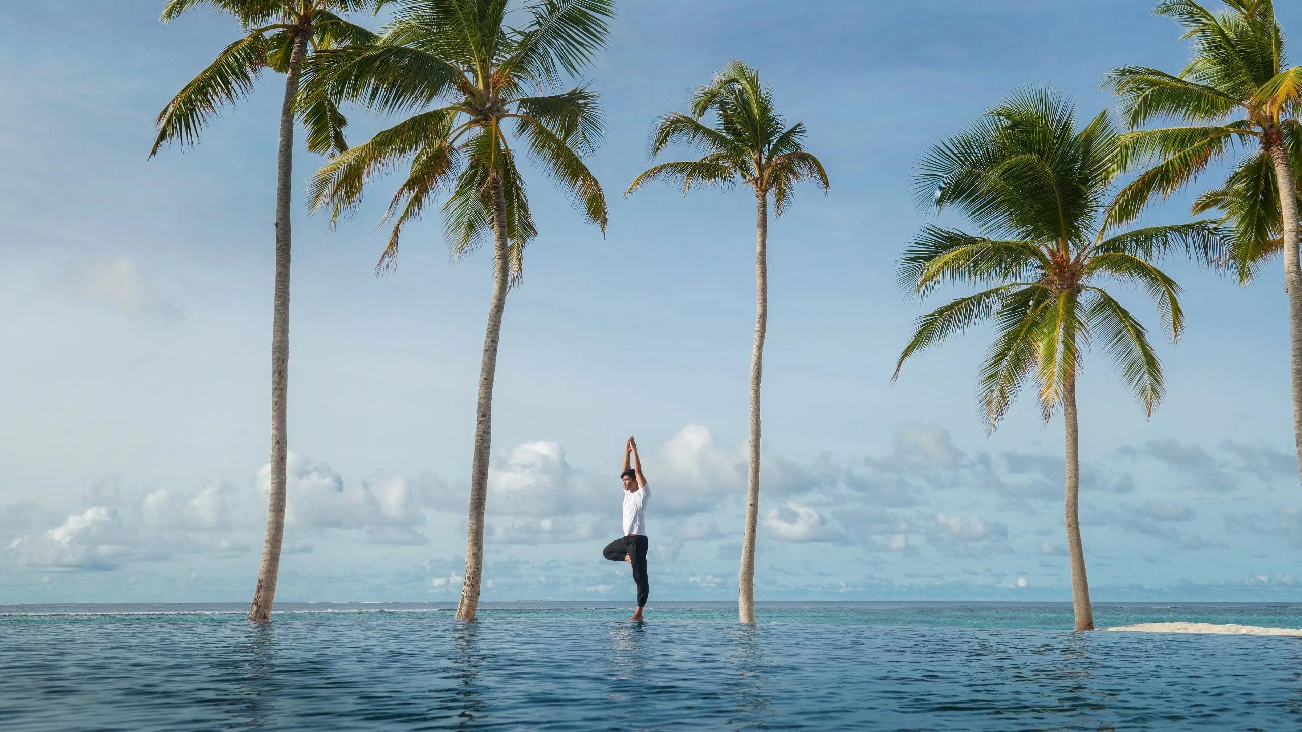 A guest practising yoga on Kothaifaru's beach at sunrise