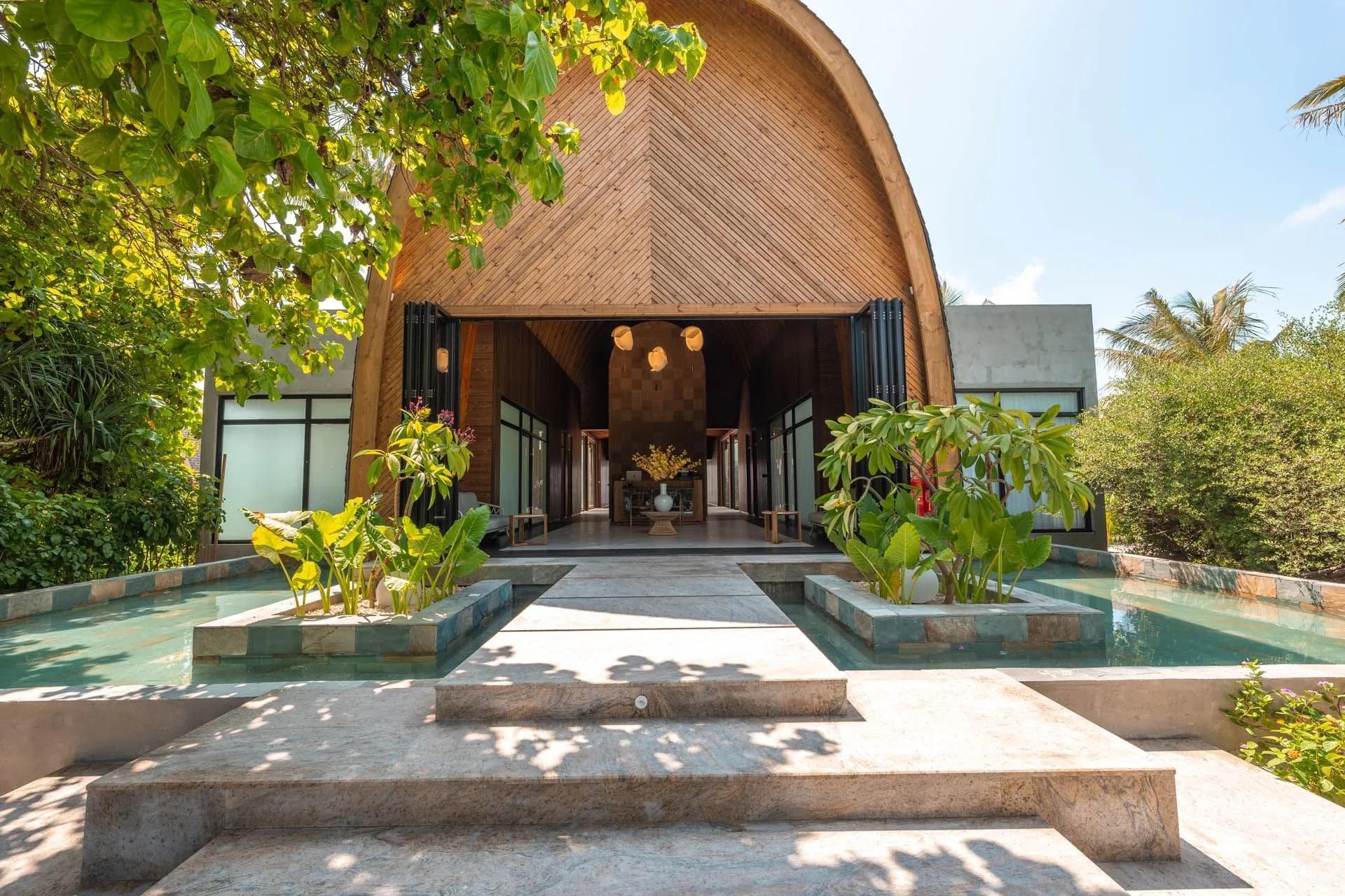 The entrance to Kandu Spa, its barrel-vaulted timber roof framed by a reflecting pool