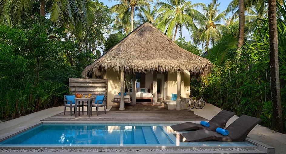A Sunrise Beach Pool Villa's 5.8-metre pool sunk into the white sand, with a daybed at the water's edge