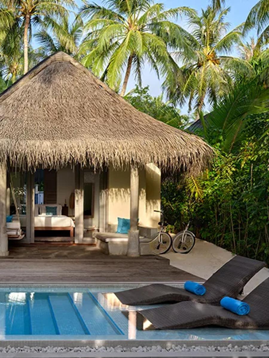 A Sunrise Beach Pool Villa's 5.8-metre pool sunk into the white sand, with a daybed at the water's edge