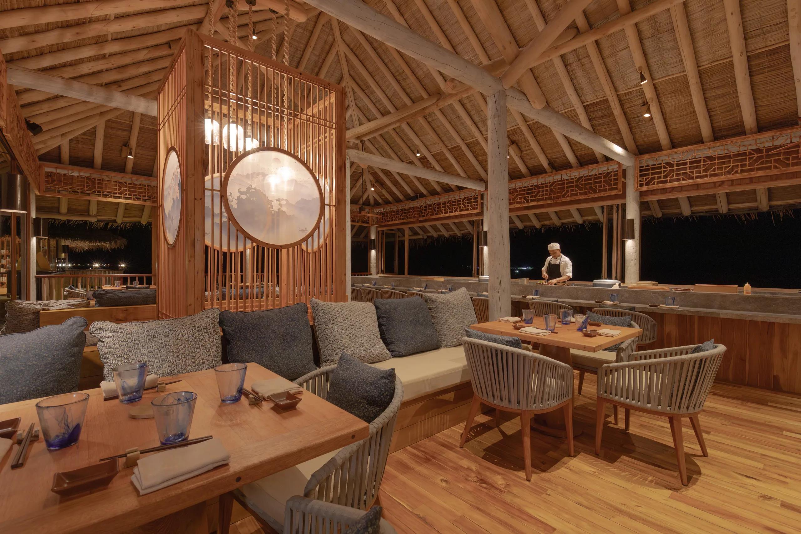 Zen's dining room at night, timber-slatted screens with backlit circular windows, and a chef at the counter beyond