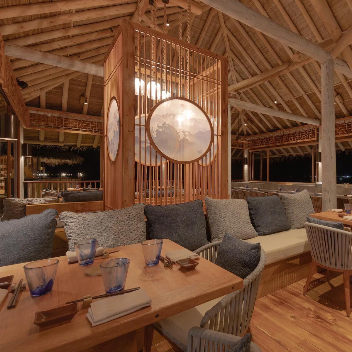 Zen's dining room at night, timber-slatted screens with backlit circular windows, and a chef at the counter beyond