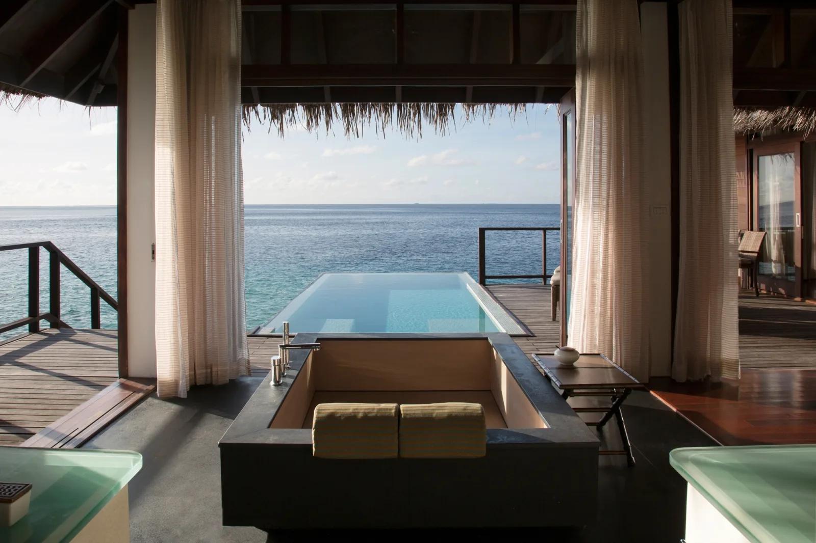 Private overwater plunge pool of an Escape Water Villa with Pool, deck furniture and open lagoon beyond