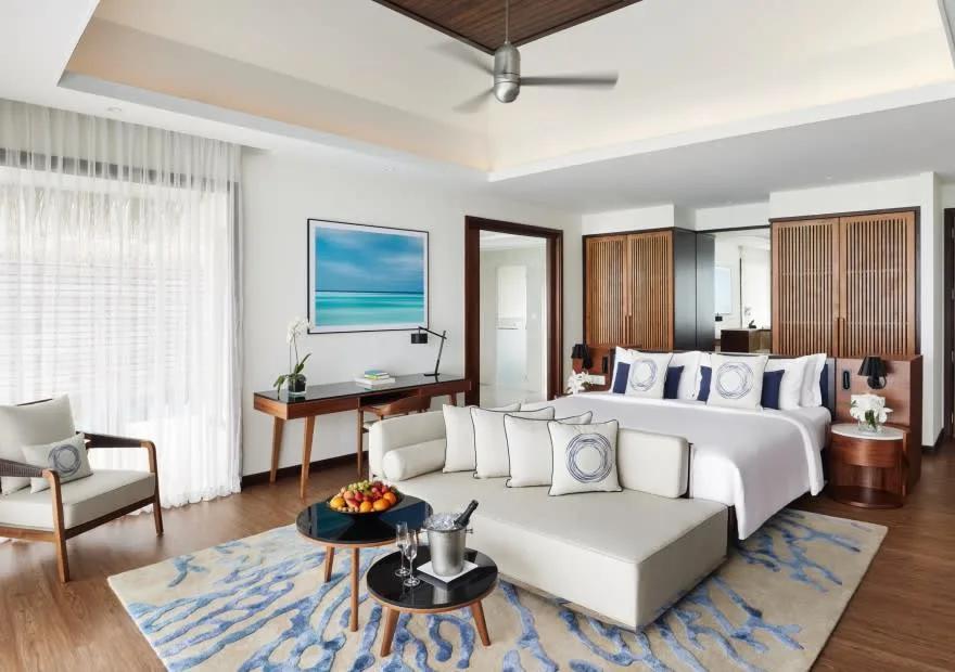 Bedroom interior of an Overwater Villa at Niyama, with seating and a desk facing the water-view terrace