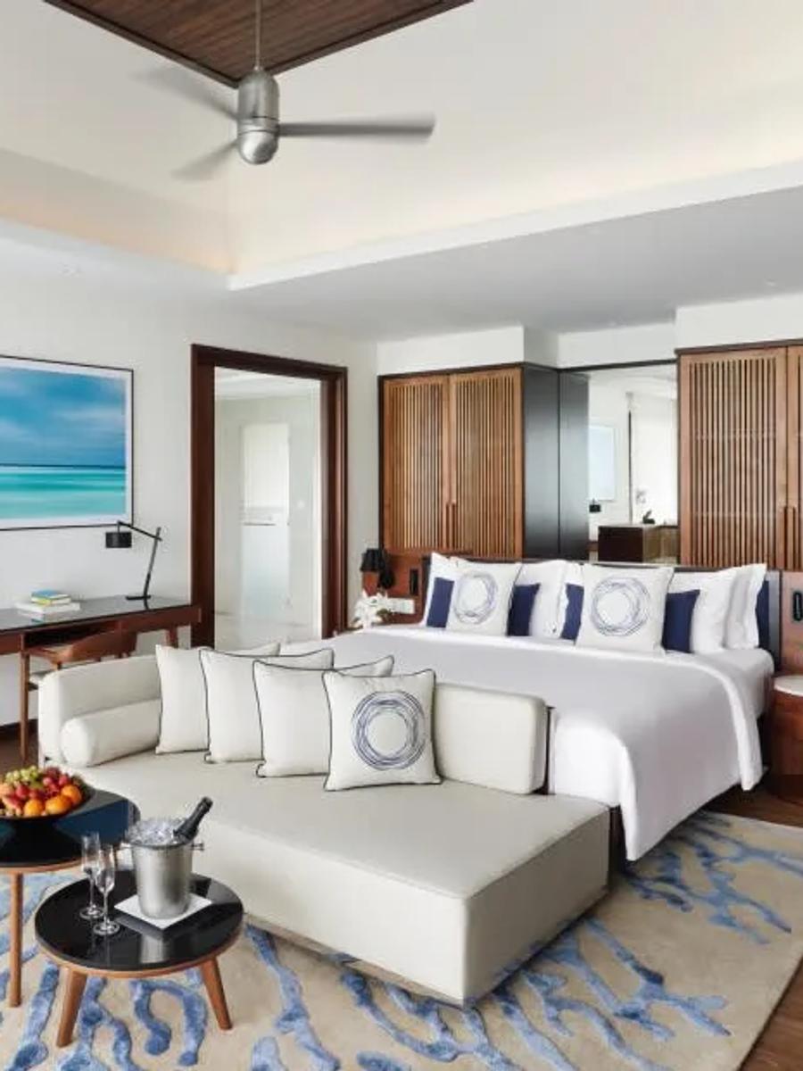 Bedroom interior of an Overwater Villa at Niyama, with seating and a desk facing the water-view terrace