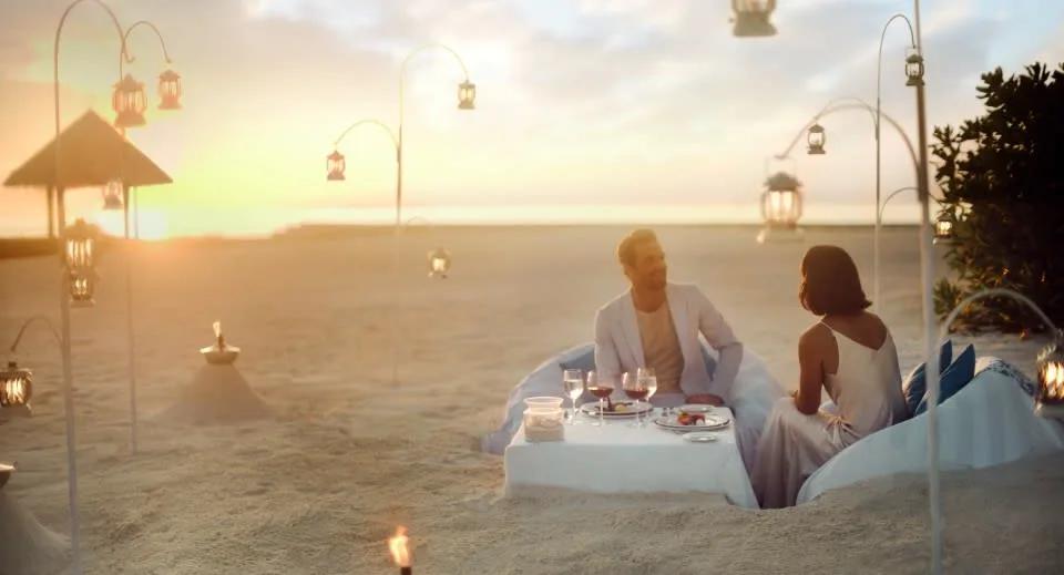 A private beach dinner table lit by lanterns at dusk, part of the resort's Dining by Design programme