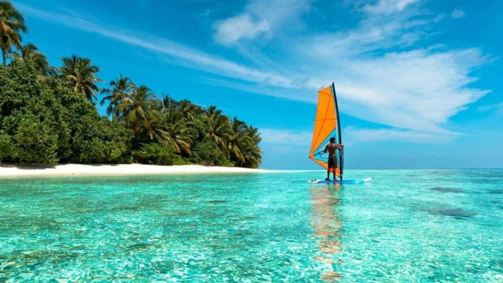 A guest windsurfing across the shallow lagoon near Jawakara's tree line