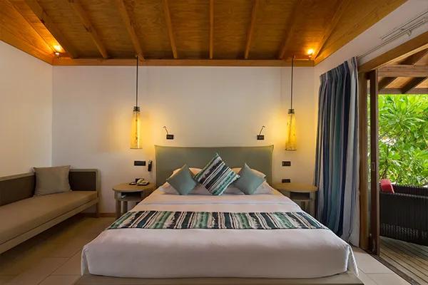 Beachfront Villa bedroom, with a low bench sofa and doors opening to greenery outside