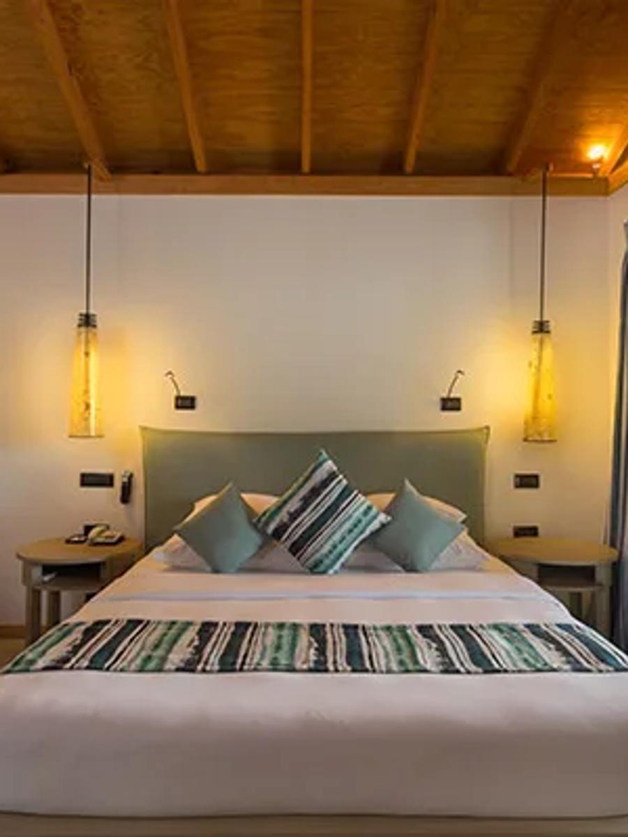 Beachfront Villa bedroom, with a low bench sofa and doors opening to greenery outside