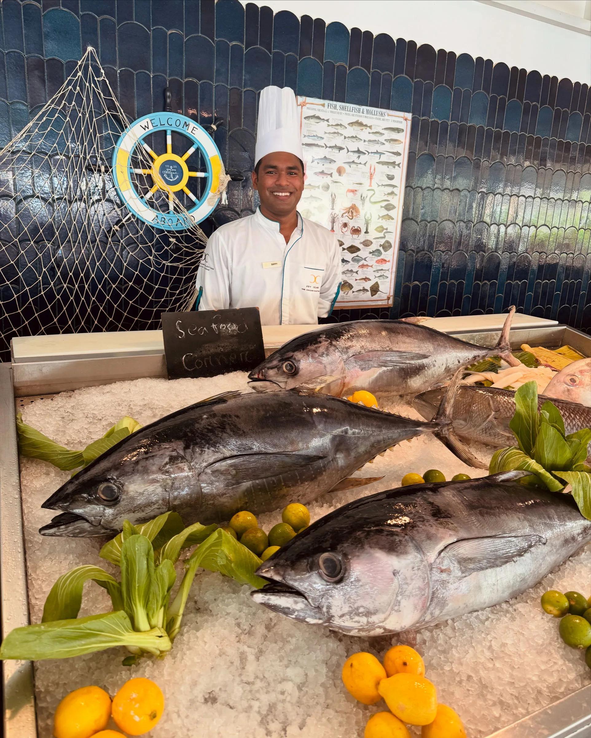 A chef stands behind The Market's seafood station, fresh tuna laid out on ice