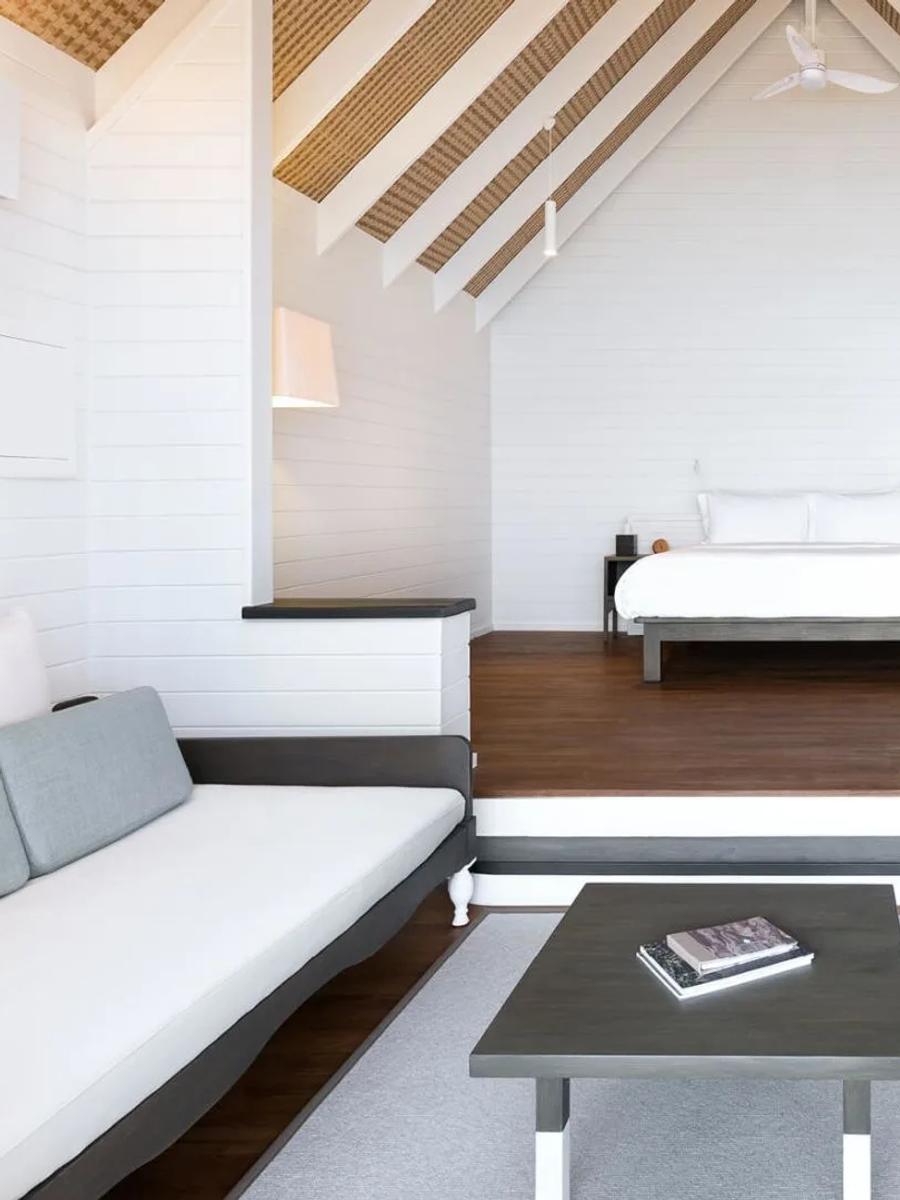 The interior of a Dhoni Water Villa, with a raised bedroom platform beneath a vaulted, dhoni-boat-shaped roof